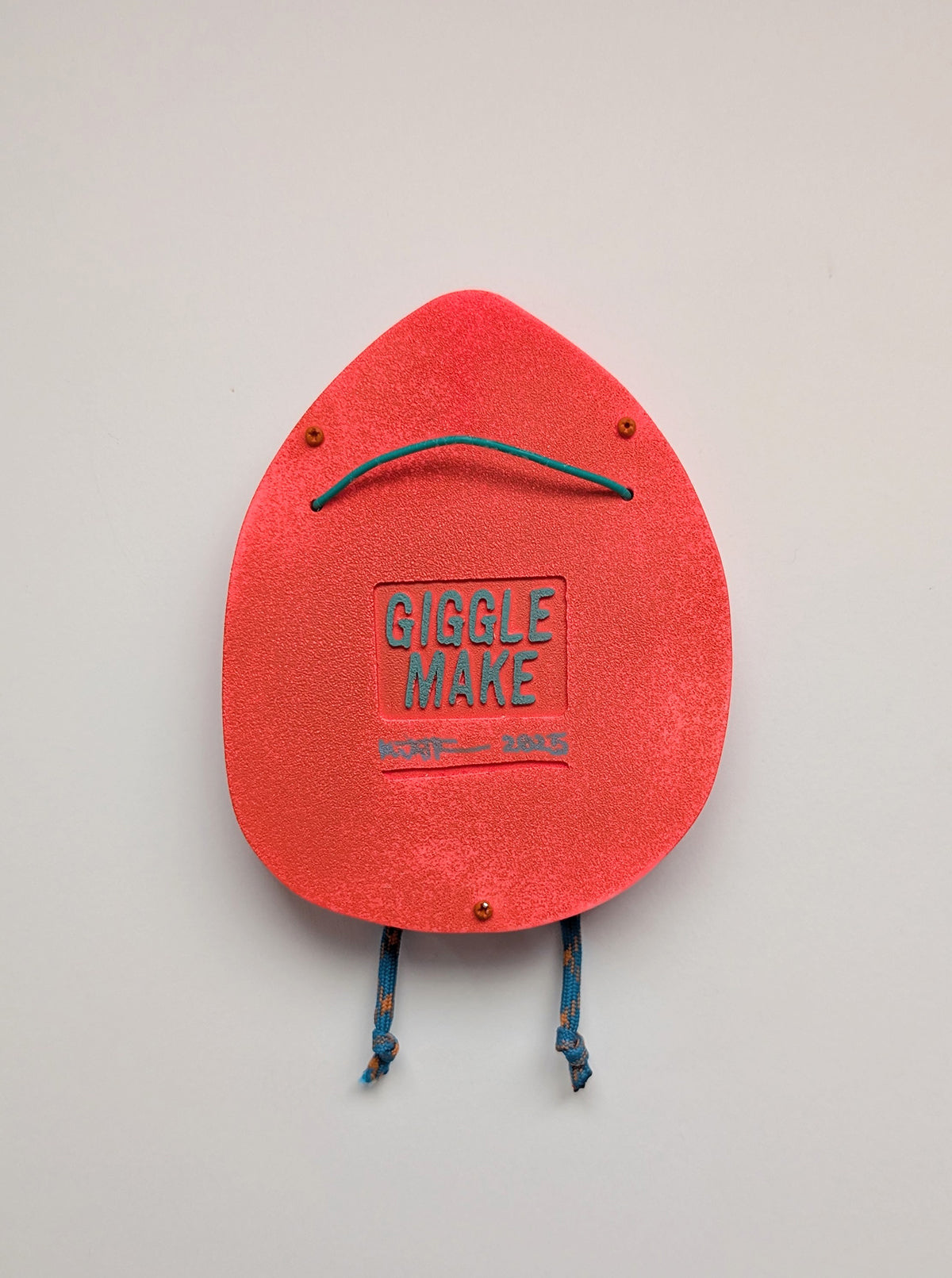 A rear view of a bright orange in color hoodie style wall sculpture that depicts hanging hardware shown with a white background.