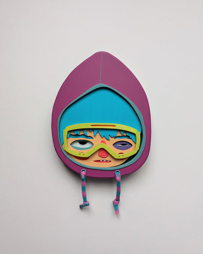 Purple hooded wall sculpture that has blue hair, bright yellow green googles on a white wall