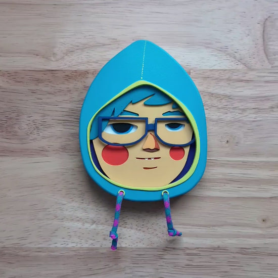 A video of a light blue hooded sculpture showing depth and size with a wood table in the background.
