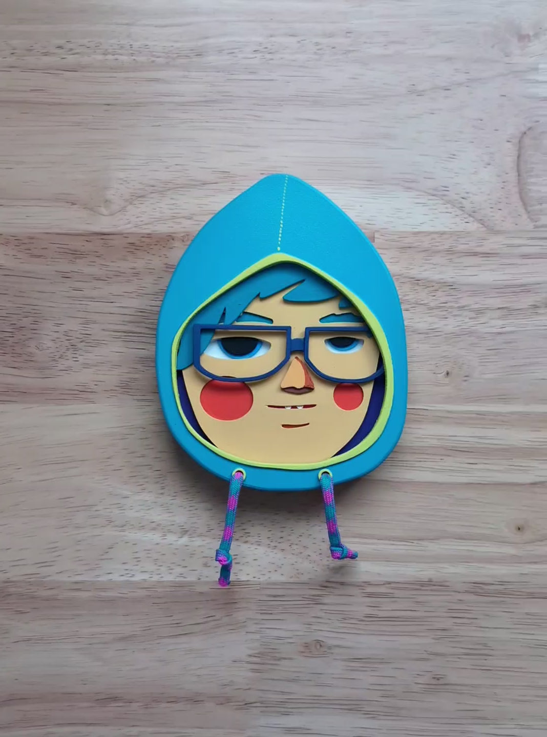 A video of a light blue hooded sculpture showing depth and size with a wood table in the background.