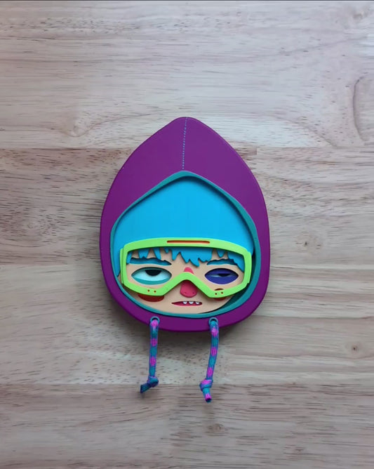 A video of a purple hooded wall art sculpture showing art size and depth with a wood table in the background.