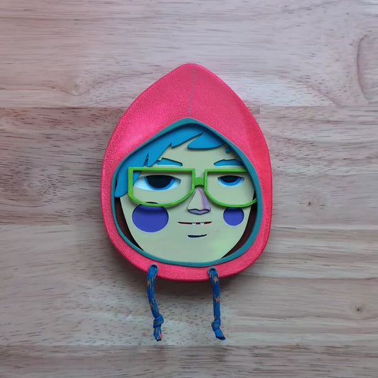 A video of a bright orange in color wall sculpture that shows depth and size on top of a wooden table.