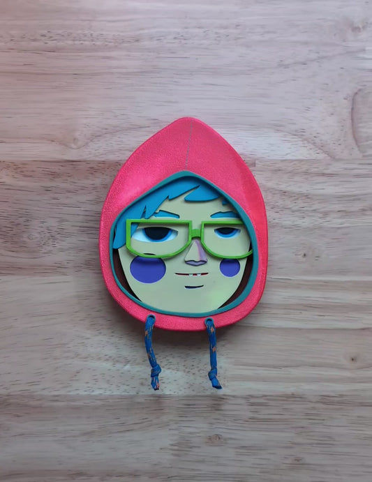 A video of a bright orange in color wall sculpture that shows depth and size on top of a wooden table.